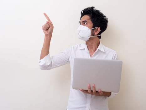 Business man in medical face mask works on laptop at home photo