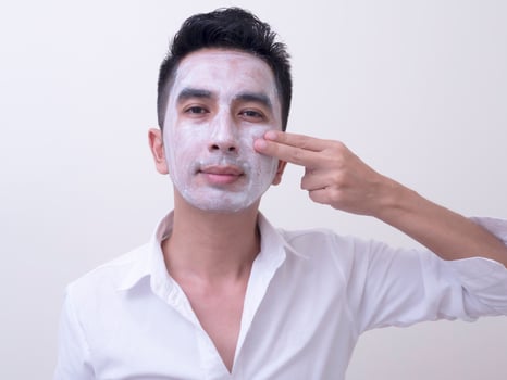 Asian handsome young man applying cream at his face with smiley face, Skin care concept photo