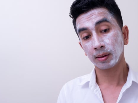 Asian handsome young man applying cream at his face with smiley face, Skin care concept photo