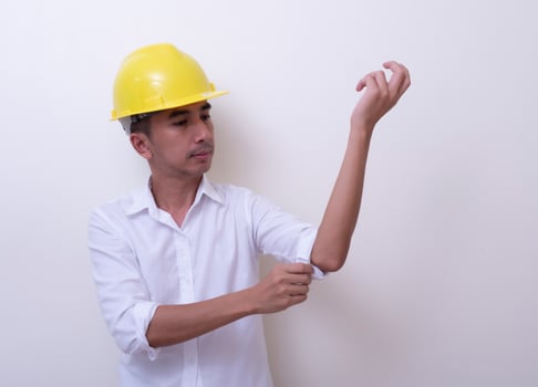 engineer with hands crossed wearing yellow helmet on white background photo