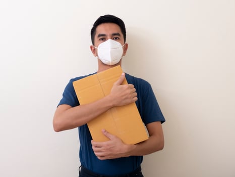 man wearing surgical mask with cardboard box on a white background photo