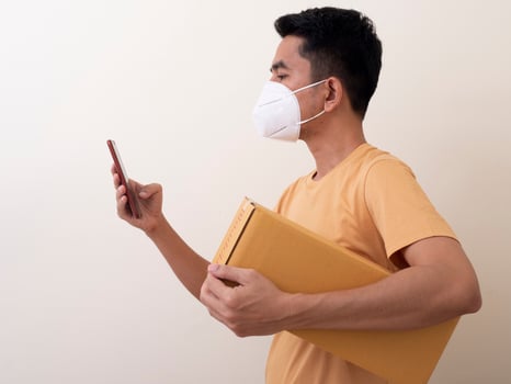 Happy delivery service employee in medical face mask carry cardboard box in hand photo