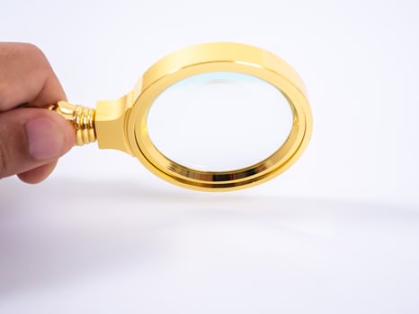 Golden magnifying glass in hand on white background photo