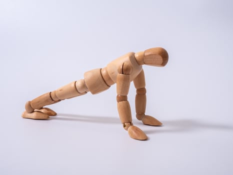 Small wooden dummy during push ups on white background photo