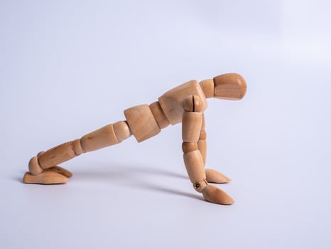 Small wooden dummy during push ups on white background photo