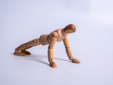 Small wooden dummy during push ups on white background photo
