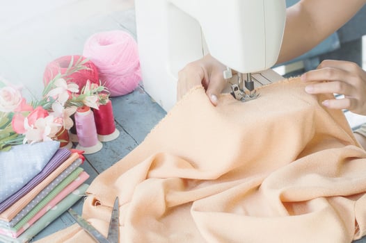 Tailor working on a sewing machine with orange fabric photo