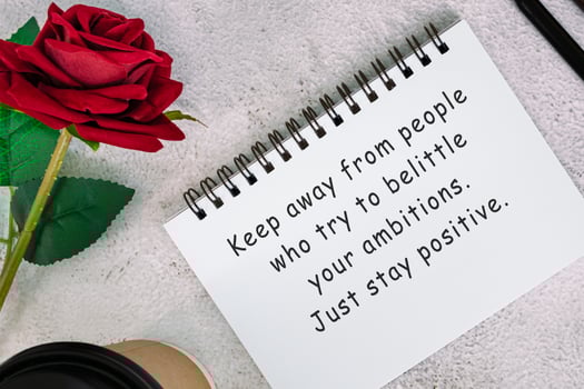 Motivational quote on a note book with roses on a desk. photo