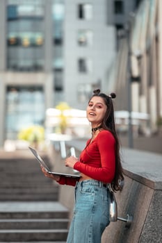 Beautiful young woman on the street using laptop photo