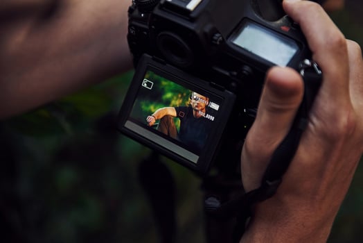 Photographer's hands holds camera. Backstage of photoshoot in the forest. Man in black shirt photo