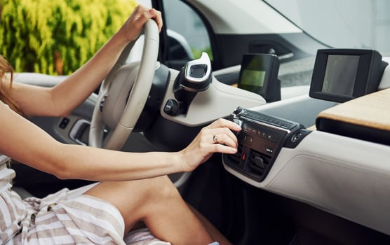 Turns the knob. Female driver inside of modern automobile. Testing brand new car photo