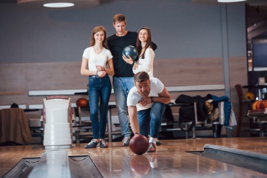 Picture in motion. Young cheerful friends have fun in bowling club at their weekends photo