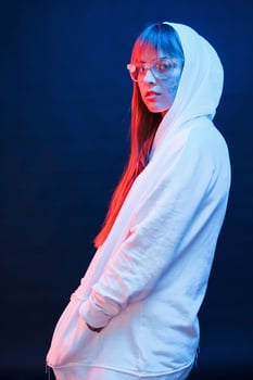 In modern white wear. Studio shot in dark studio with neon light. Portrait of young girl photo