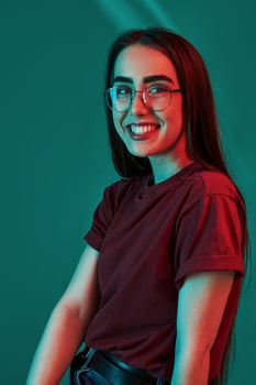 Having good mood. Studio shot indoors with neon light. Portrait of beautiful young girl photo