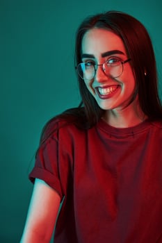 Toothy smile. Studio shot indoors with neon light. Portrait of beautiful young girl photo