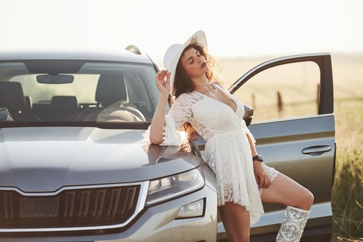 Calm and quiet. Girl in white clothes posing near the modern luxury automobile outdoors photo