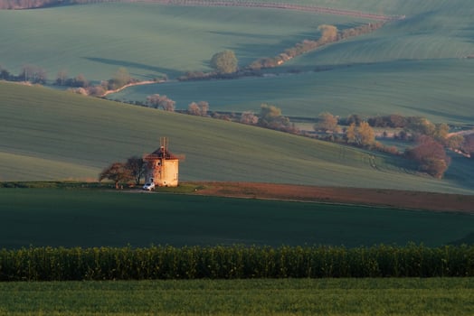 Majestic landscape of field in the evening. Windmill in the center of meadow photo