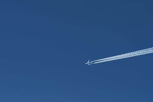 Modern plane flying high in the blue sky at sunny day. Speed and energy photo