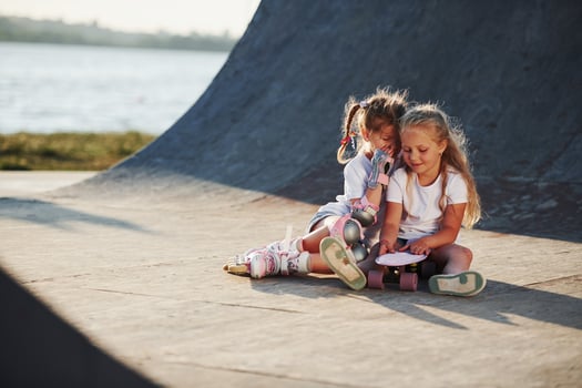 Relaxing and have conversation. On the ramp for extreme sports. Two little girls with roller skates outdoors have fun photo