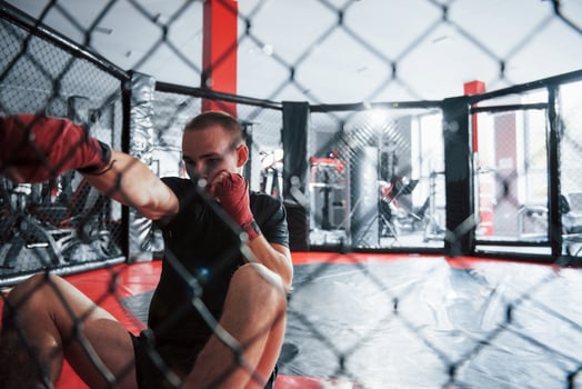 From down position. Young boxer in red bandages have exercise. In the gym on the cage photo