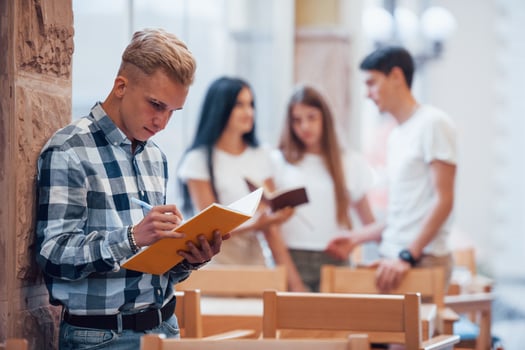 Guy reads his notepad. Four young students in casual clothes have meeting at rainy day photo