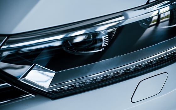 Front part of brand new modern white car. Parked at showroom. Reflection in the headlights photo