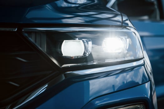 Front part of brand new modern blue car. Parked at showroom. Reflection in the headlights photo