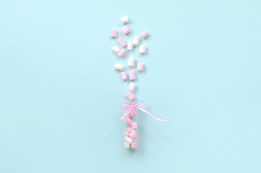 Marshmallow is sprayed from a small glass container on a blue background. photo