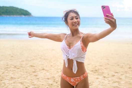 Young Beautiful woman in Bikini listening to music and using smartphone on the beach,  Summer, vacation, holidays, Lifestyles concept. photo