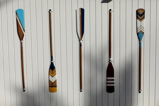 four colourful wooden paddles hangs on a white wall. canoe oars for active water sport. holiday vacation. High quality photo