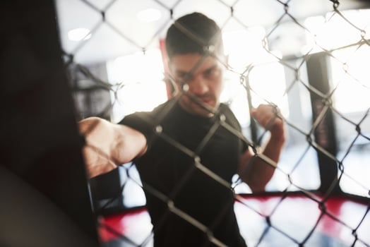 Blurred picture. Strong man is boxing in the gym behind the fence. Haves daily exercise photo