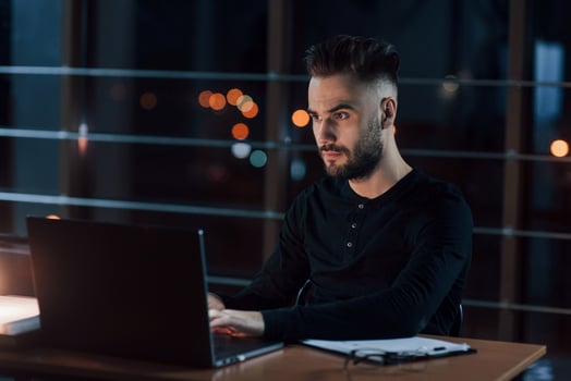Concentrated at job. Stylish young businessman works alone in the office at nightime photo