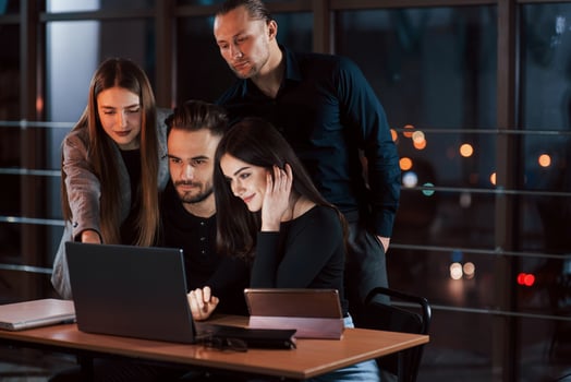 Guy teaches his employees. Team of young business people works on their project at night time in the office photo