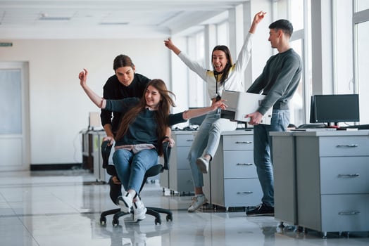 Man holds printer. Having fun in the office. Young people have a break and driving by using a seat photo