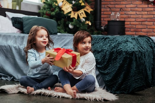 Christmas holidays with gifts for these two kids that sitting indoors in the nice room near the bed photo