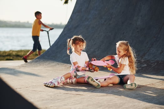 Trying new skate. Two cute female kids have fun outdoors in the park photo