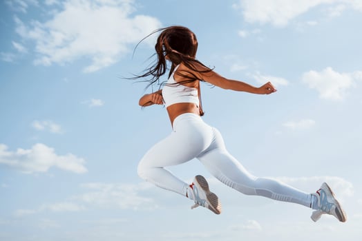 Up in the sky. Female runner in white sportive clothes doing fitness photo