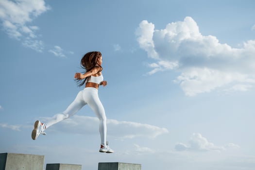 Up in the sky. Female runner in white sportive clothes doing fitness photo