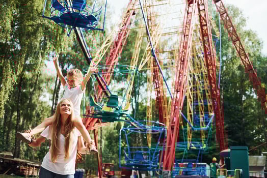 Cheerful little girl her mother have a good time in the park together near attractions photo