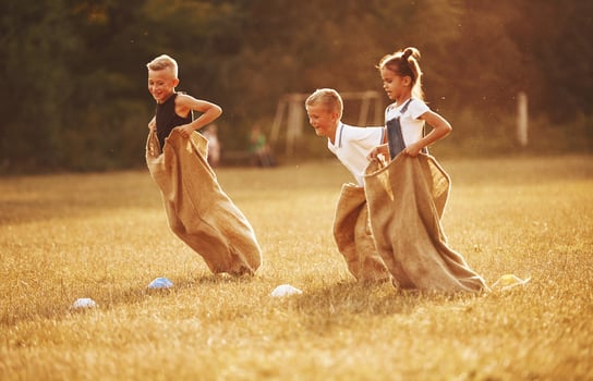 Jumping sack race outdoors in the field. Kids have fun at sunny daytime photo