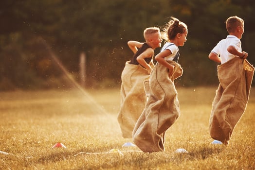 Jumping sack race outdoors in the field. Kids have fun at sunny daytime photo