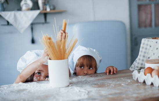 Having fun with spaghetti. Family kids in white chef uniform preparing food on the kitchen photo