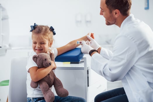 Blood sampling. Little girl with her teddy bear is in the clinic with doctor photo