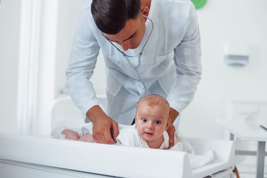 Young pediatrician is with little baby in the clinic at daytime photo