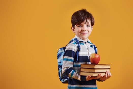 Portrait of young smart schooler in the studio against yellow background photo
