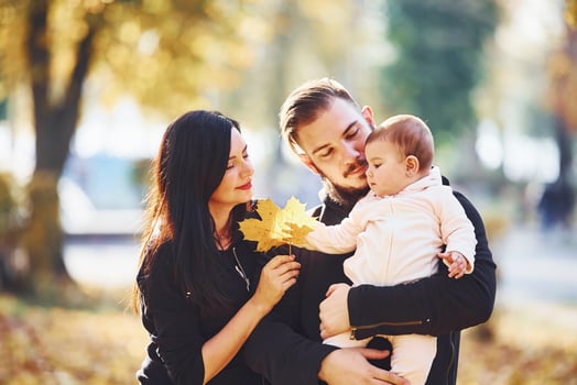 Cheerful family having fun together with their child in beautiful autumn park photo