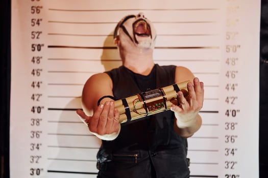 Portrait of man that is on the thematic halloween party in scary black metal makeup and costume with bomb in hands photo