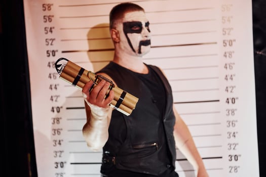 Portrait of man that is on the thematic halloween party in scary black metal makeup and costume with bomb in hands photo
