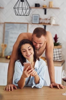 Couple together in the kitchen at morning time with mobile phone photo