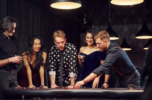 Standing by the table. Group of elegant young people that playing poker in casino together photo